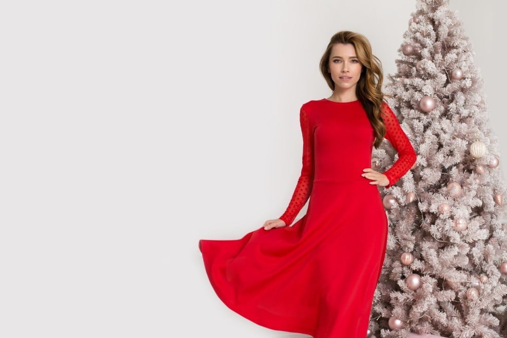 Kvinde i en flot rød julekjole foran et juletræ